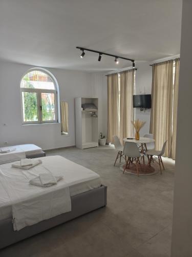 a white room with a bed and a table and chairs at Melina Rooms in Dhërmi