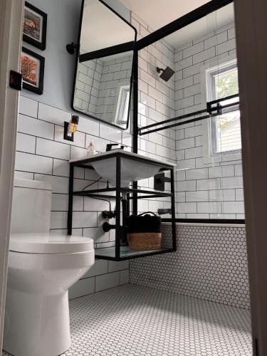 a white bathroom with a toilet and a mirror at Eclectic & Fun Custom Home in Shawnee