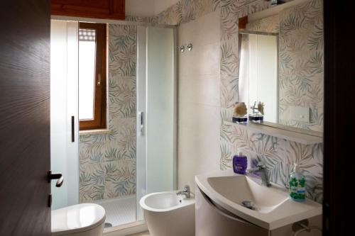 a bathroom with a sink and a toilet and a mirror at Vitti Apartment in Nettuno