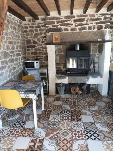 a living room with a fireplace and a table and chairs at La Cahute, gîte étape in La Forêt-Auvray