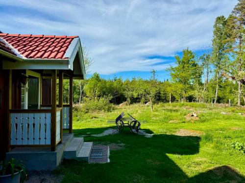 a small house with a bench in the grass at Holiday home Småland Siggamåla in Husjönäs