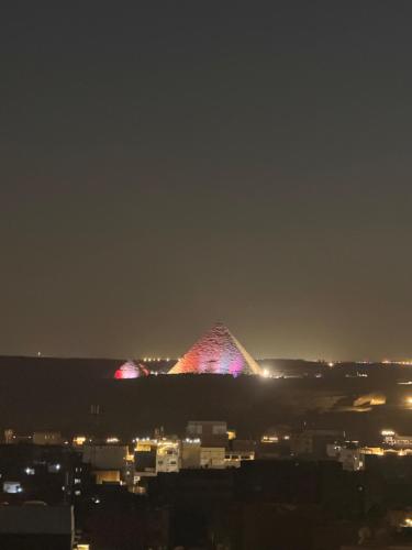 a pyramid lit up at night in a city at Pyramids gardens guest House in ‘Ezbet `Abd el-Ḥamîd