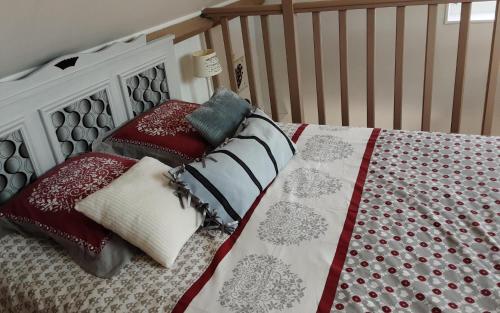 a bed with red and white pillows and a crib at Le Petit Montceaux in Le Val-Saint-Père
