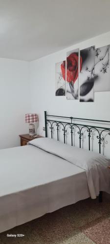 a white bed with three pictures on the wall at casa al mare kalispera in Marina di Mancaversa