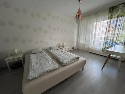a bedroom with a bed and a table and a window at Large apartment in the centre of Jyväskylä with private swimming pool and sauna in Jyväskylä