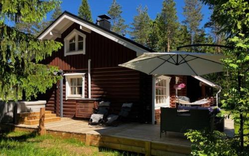 a house with a deck with an umbrella at Honkahimos 7, Pohjois-Huippu, Jämsä in Jämsä