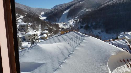 a view of a snow covered mountain from a window at Eleni's Guesthouse in Pisoderi