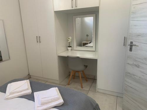 a bedroom with a mirror and a bed with a chair at OysterCatcher Self-Catering Accommodation Strand in Cape Town