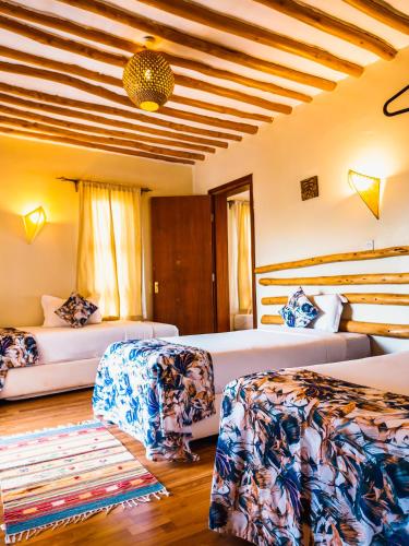 a hotel room with two beds and a rug at The Last Village Lodge in Athi River