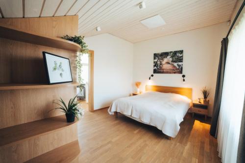a bedroom with a white bed and wooden floors at MADARAS Country house in Ventava