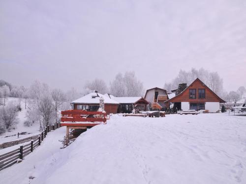 a snow covered yard with a house and a bridge at Rancho Zapotoczny in Łagów