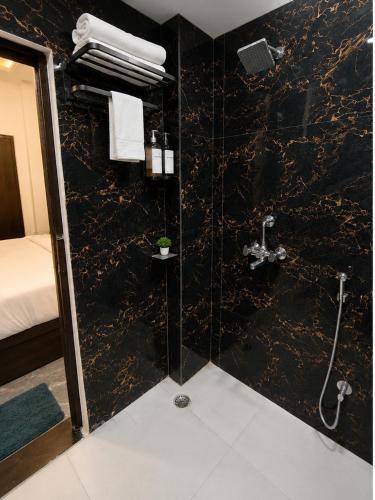a bathroom with a shower with a black marble wall at Barsana Suites in Vrindāvan