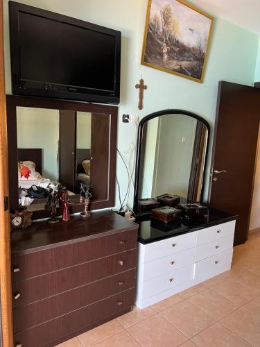 a dresser with a mirror and a tv on top at Aqua Mare Seaside Experience in Pyrgadikia