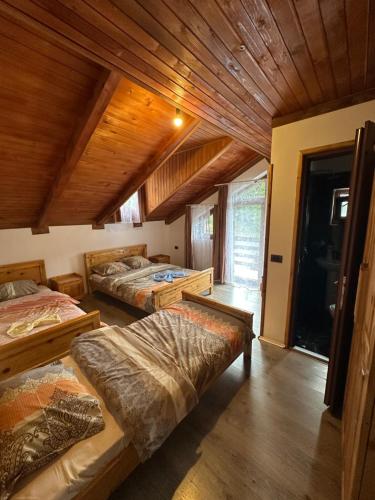 a bedroom with three beds and a wooden ceiling at Natyra balcony in Valbonë