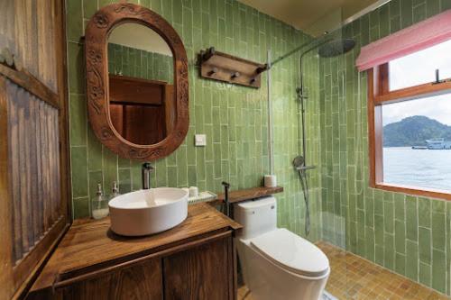 a bathroom with a sink and a toilet and a mirror at Petit Prince Cruise in Cat Ba