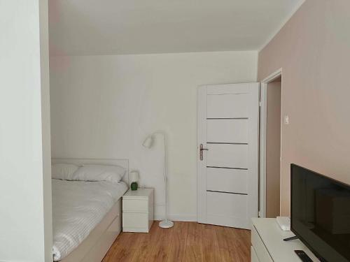 a white bedroom with a bed and a television at Cichy Kącik in Wadowice