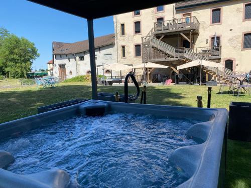 a hot tub in a yard next to a building at Le Moulin d'Oscar & Spa - Mulhouse Nord in Baldersheim