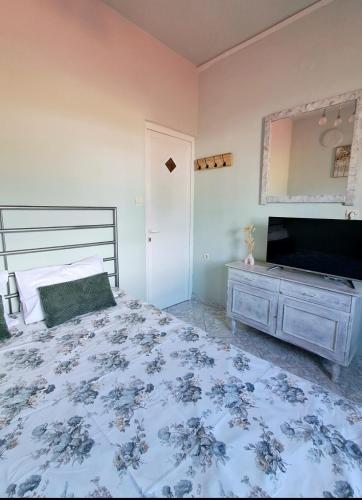 a bedroom with a bed and a dresser and a television at Helen's studio in Leptokarya