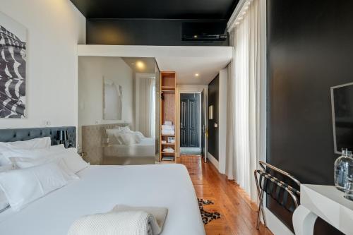 ein Schlafzimmer mit einem großen weißen Bett und ein Badezimmer in der Unterkunft RM The Experience - Small Portuguese Hotels in Setúbal