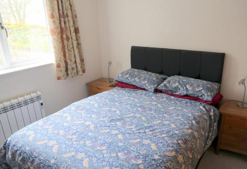 a bedroom with a bed with a blue comforter and a window at Gap Cottage on Hadrian's Wall in Brampton