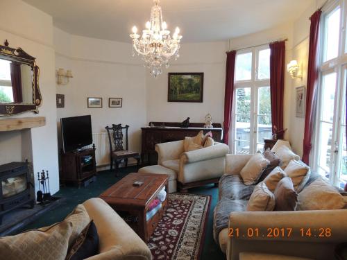 a living room with couches and a chandelier at Orchard House Hotel in Lynmouth