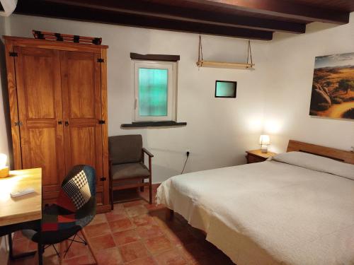 a bedroom with a bed and a desk and a chair at El Silencio in Mesegal