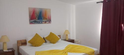 a bedroom with a bed with yellow sheets and a painting at Sunrise house in Ribeira Grande