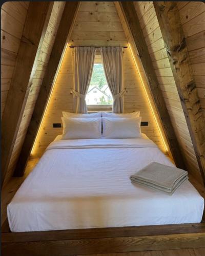 a white bed in a attic with a window at Etno Selo Dolina Pive in Plužine