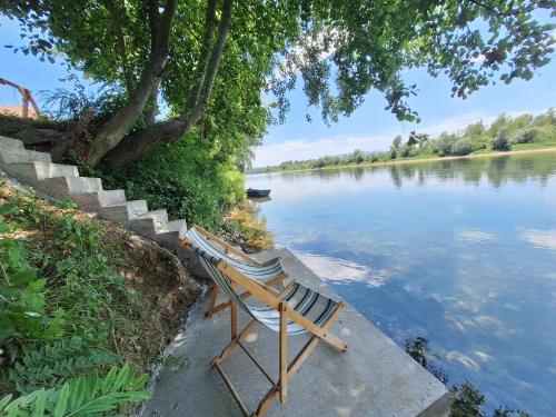 a couple of chairs sitting next to a river at Brvnara Bata - Vikendica na Drini in Lipnički Šor