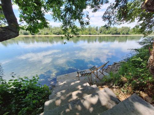 a bench sitting on the edge of a lake at Brvnara Bata - Vikendica na Drini in Lipnički Šor