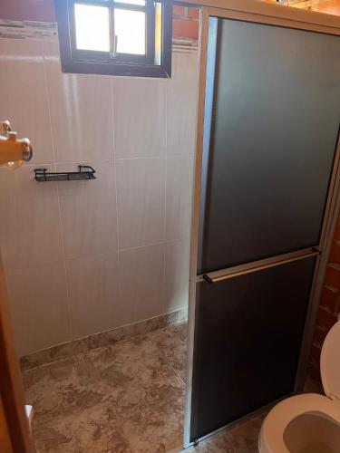 a bathroom with a toilet and a black refrigerator at Bella Vite in São José dos Pinhais