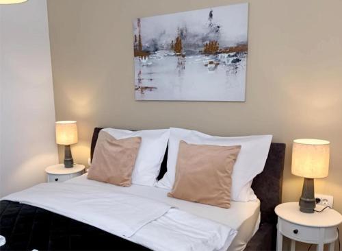 a bed with white sheets and pillows and two lamps at Apartman Ines in Pribislavec