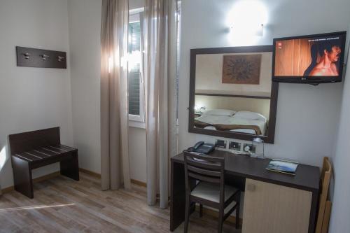 een kamer met een bureau, een spiegel en een bed bij Hotel Lauro in Gravedona