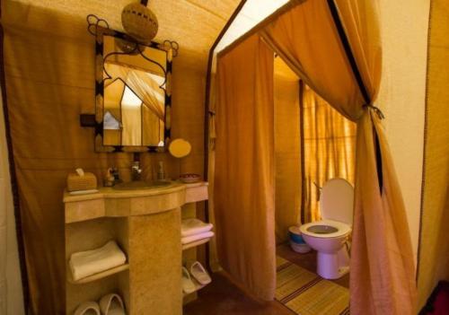 a small bathroom with a toilet and a sink at Shining Luxury Camp in Merzouga
