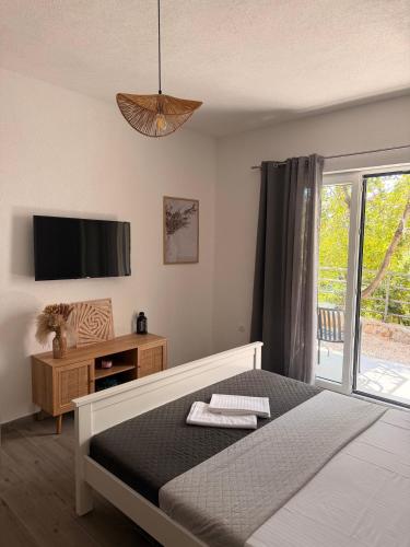 a bedroom with a bed and a tv and a window at Quattro Rocce Apartments Zelen in Sutomore