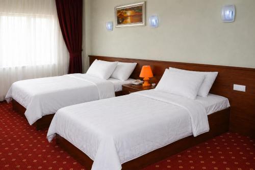 a hotel room with two beds with white sheets at Sultan Otel Mardin in Sultan Koyu