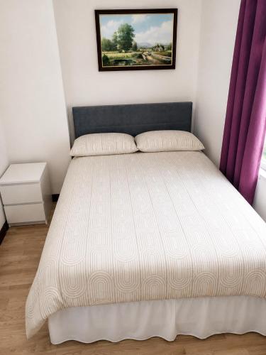 a bedroom with a white bed with purple curtains at Hillview Cottage Eskra in Curr