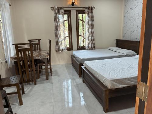 a bedroom with two beds and a table and chairs at Velu House - 2-Room Apartment in Jaffna