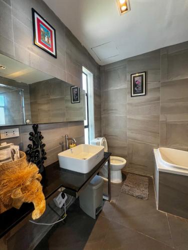a bathroom with a sink and a toilet and a mirror at The Hermitage Tagaytay-Presidential Suite in Malabag