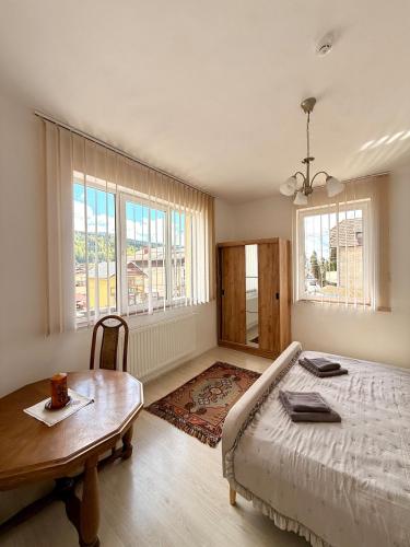 a bedroom with a bed and a table and windows at Mountain View House Busteni in Buşteni