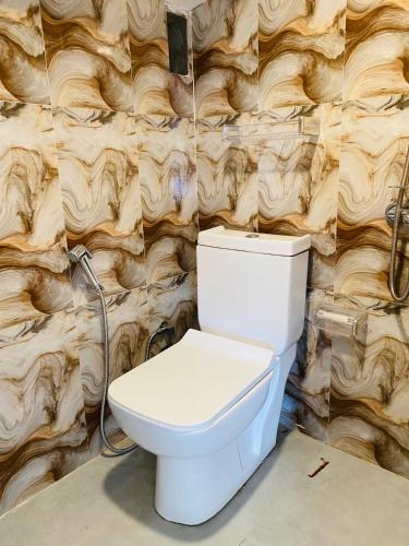 a white toilet in a bathroom with a wall at Infinity Winter Resort in Nuwara Eliya