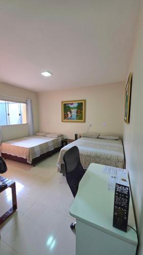 a room with two beds and a desk in it at Pássaros do Cerrado Suítes in Alto Paraíso de Goiás
