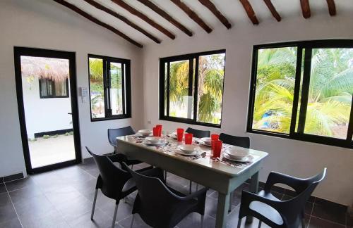 ein Esszimmer mit Tisch, Stühlen und Fenstern in der Unterkunft Valentina Holbox by Las Flores Vacation Rentals in Holbox