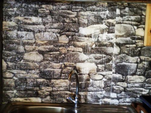 a kitchen sink with a stone wall behind it at Wagon Wheel Gabin in Chrissiesmeer