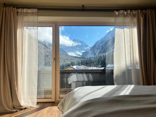 a bedroom with a large window with a mountain view at Alpine Apartments St-Sigmund in Sankt Sigmund im Sellrain
