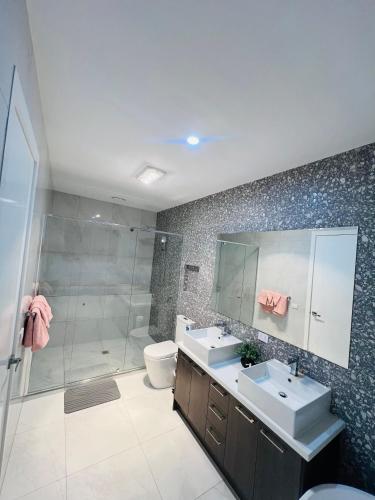 a bathroom with a shower and two sinks and a toilet at Mickleham Prestige Homestay in Mickleham
