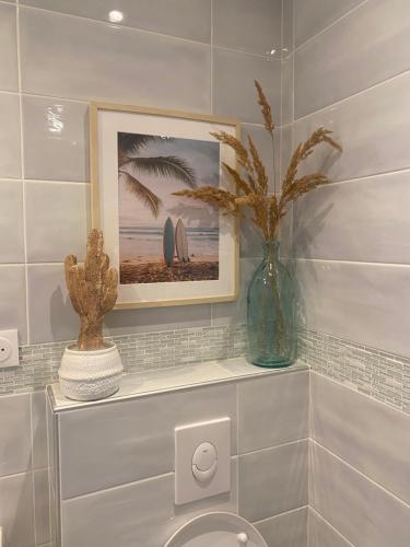 a bathroom with a picture and a vase with a plant at Maison proche plage et Golf in Moliets-et-Maa