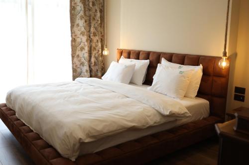 a large bed with white sheets and pillows at Mugull Agrotourism Hotel in Tirana