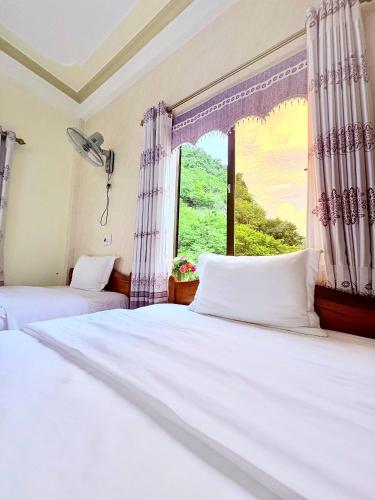 two beds in a room with a window at Hoa Phuong Hotel Phong Nha in Phong Nha