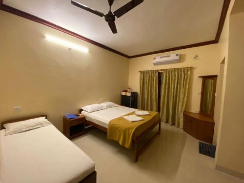 a bedroom with two beds and a ceiling fan at Henry's Place in Calangute